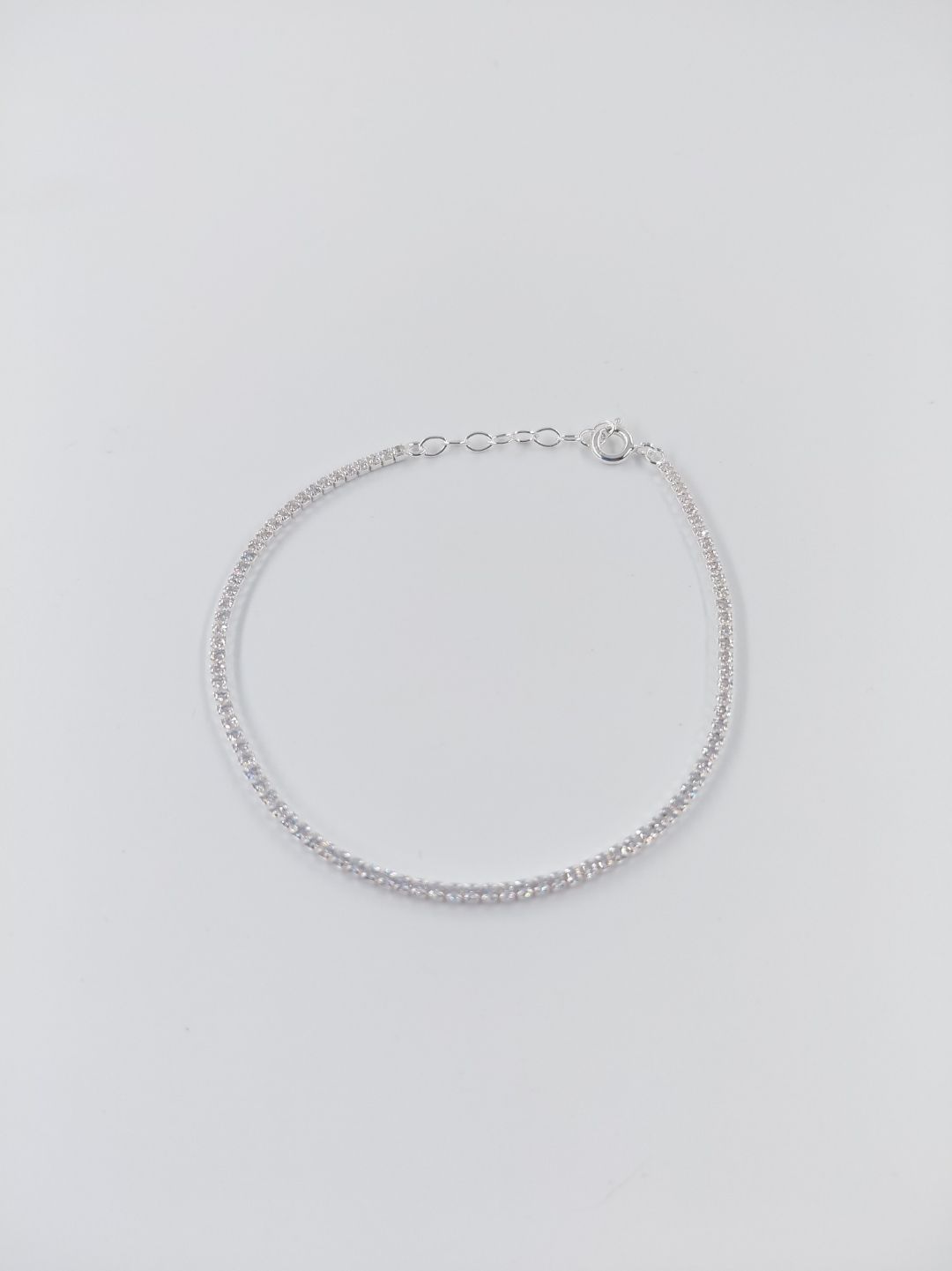 Pulsera de cadena plateada sobre un fondo gris claro