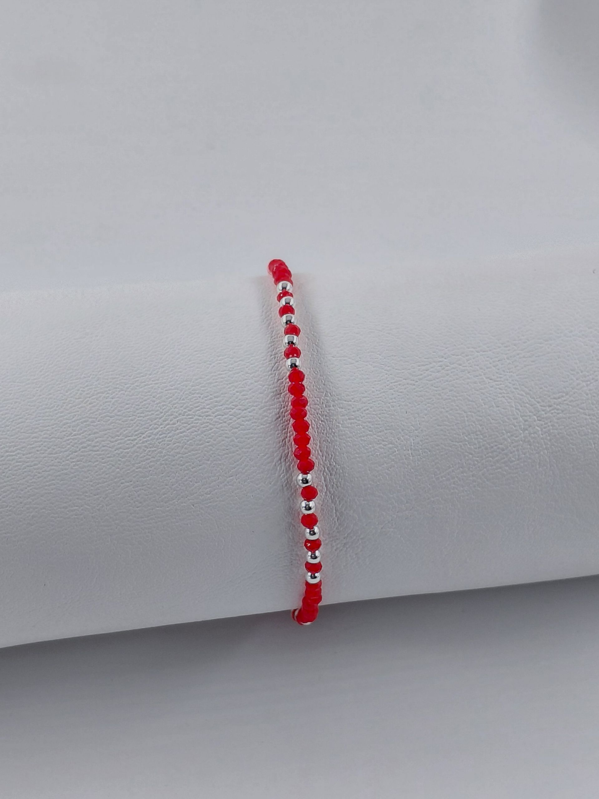Pulsera de cuentas rojas con cierre plateado sobre fondo blanco