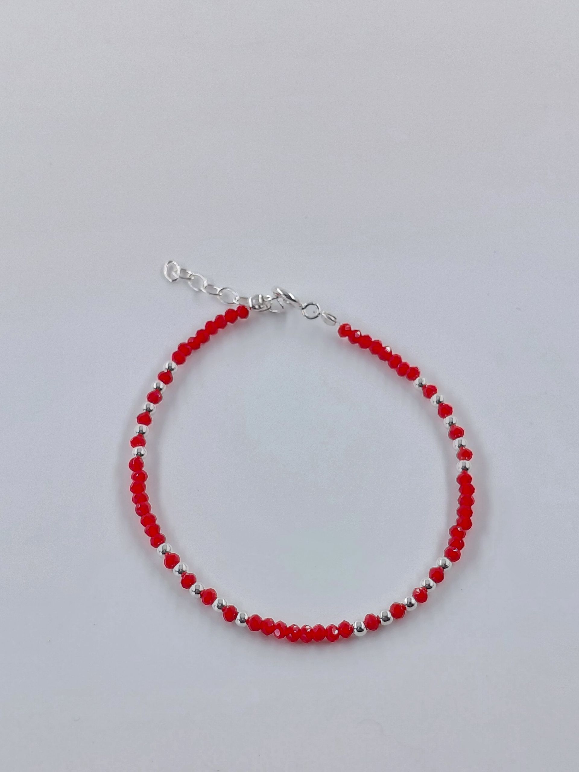 Pulsera de cuentas rojas con cierre plateado sobre fondo blanco