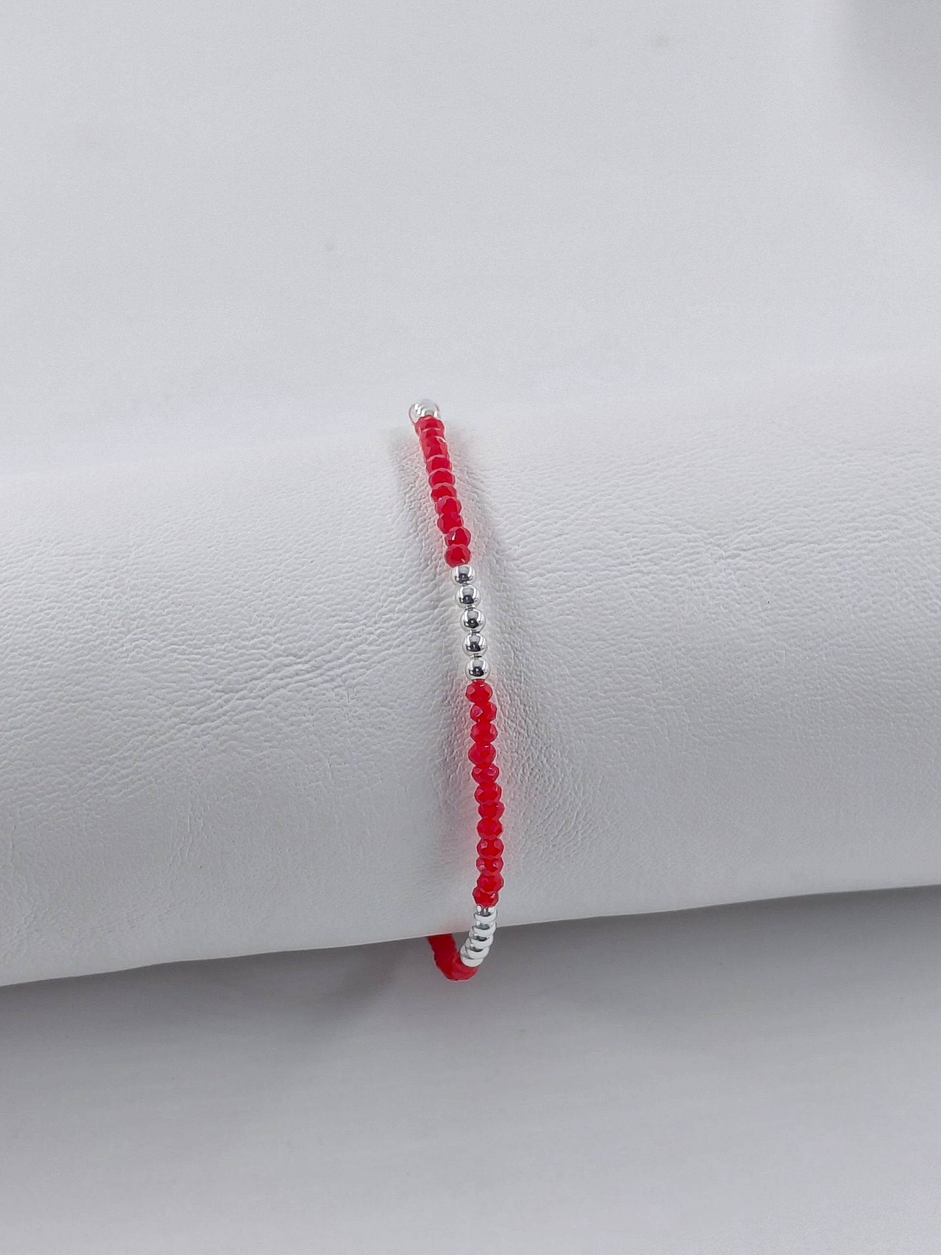 Pulsera de cuentas rojas y blancas sobre un fondo gris claro