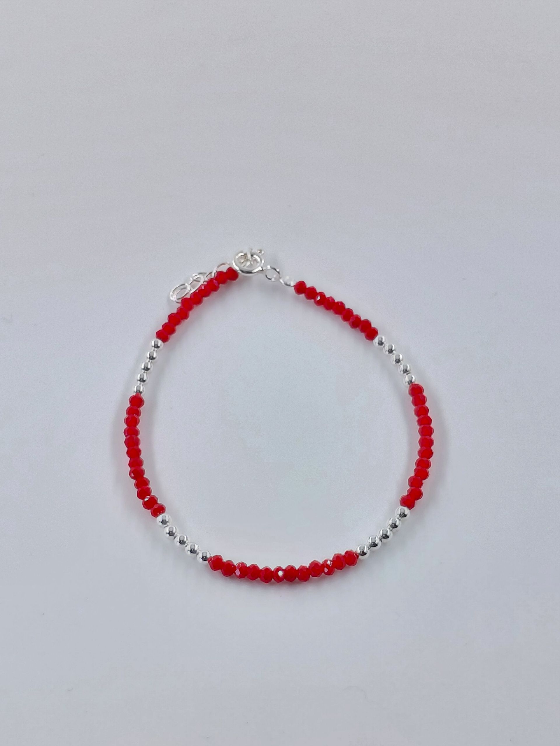 Pulsera de cuentas rojas y blancas sobre un fondo gris claro