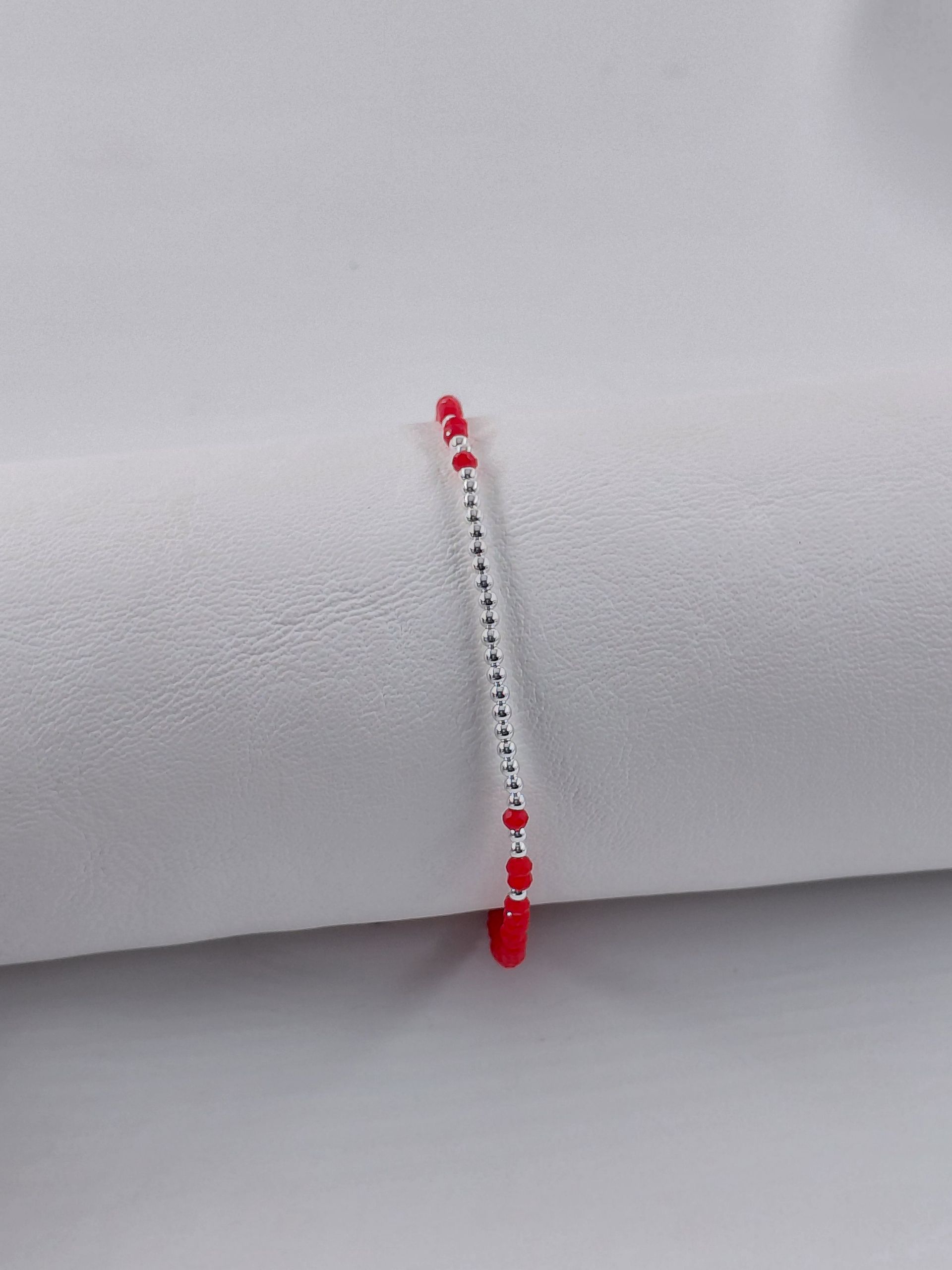 Pulsera de cuentas rojas y plateadas sobre un fondo claro