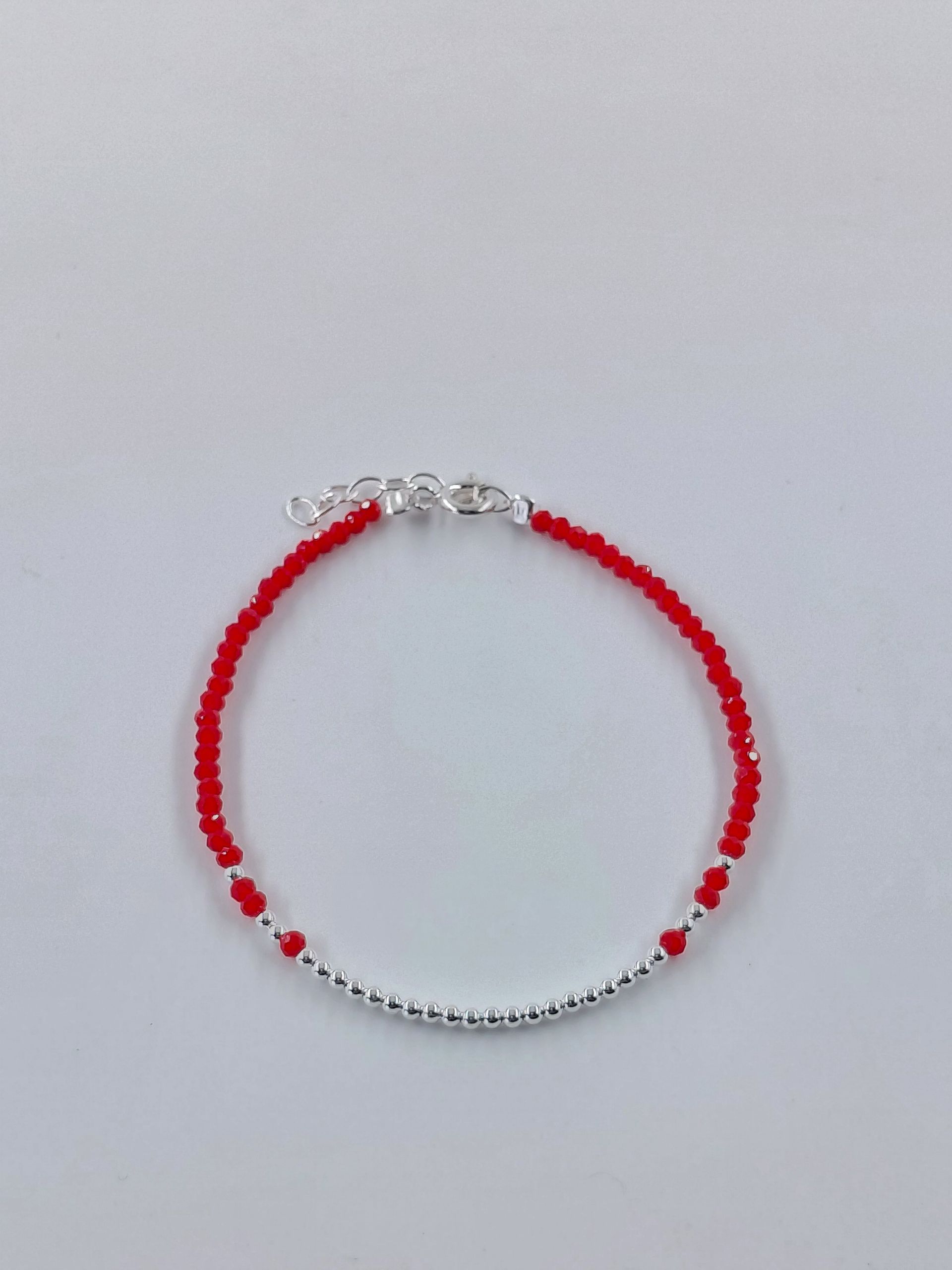 Pulsera de cuentas rojas y plateadas sobre un fondo claro