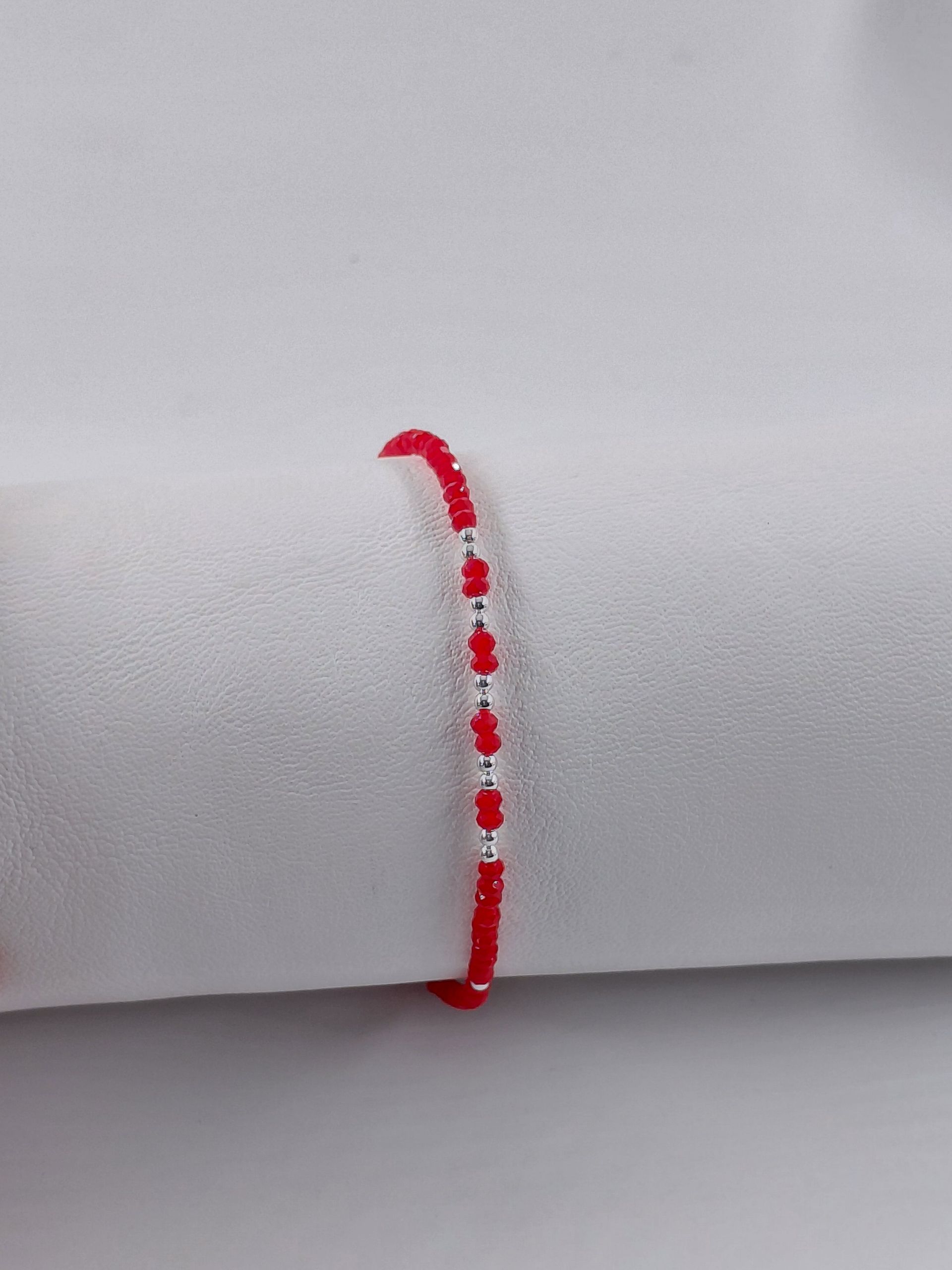 Pulsera de cuentas rojas con cierre plateado sobre fondo gris claro