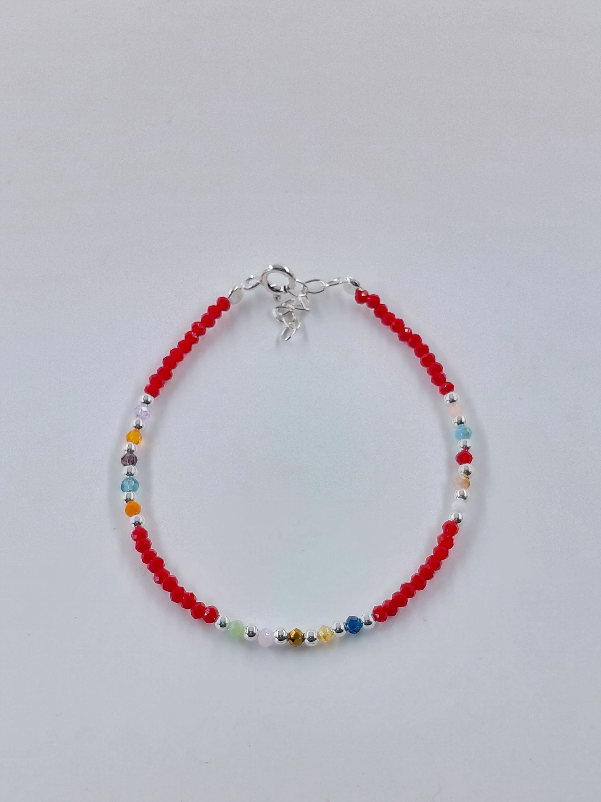 Pulsera colorida con cuentas rojas y multicolores sobre un fondo blanco.