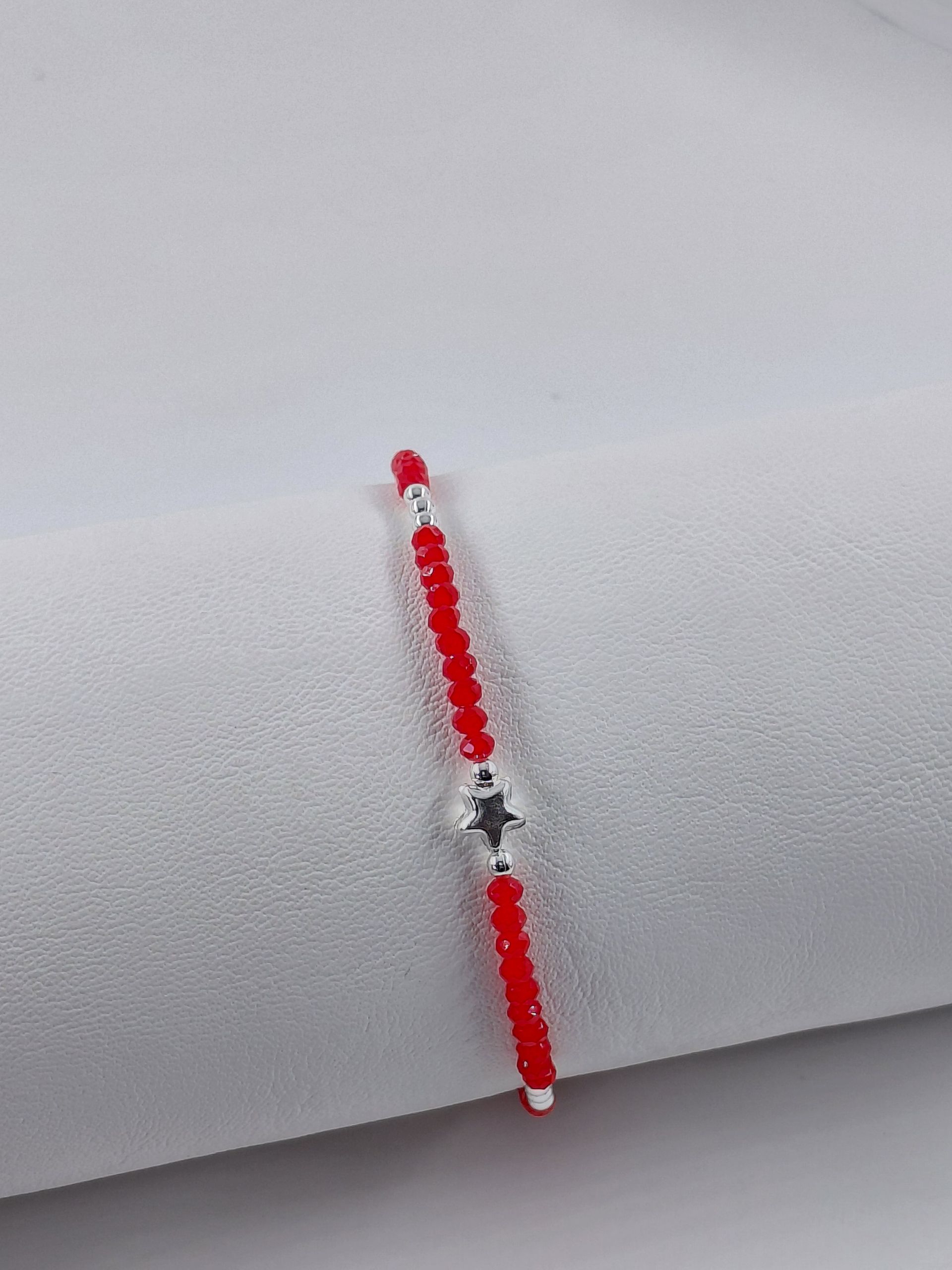 Pulsera de cuentas rojas y plateadas sobre un fondo gris claro