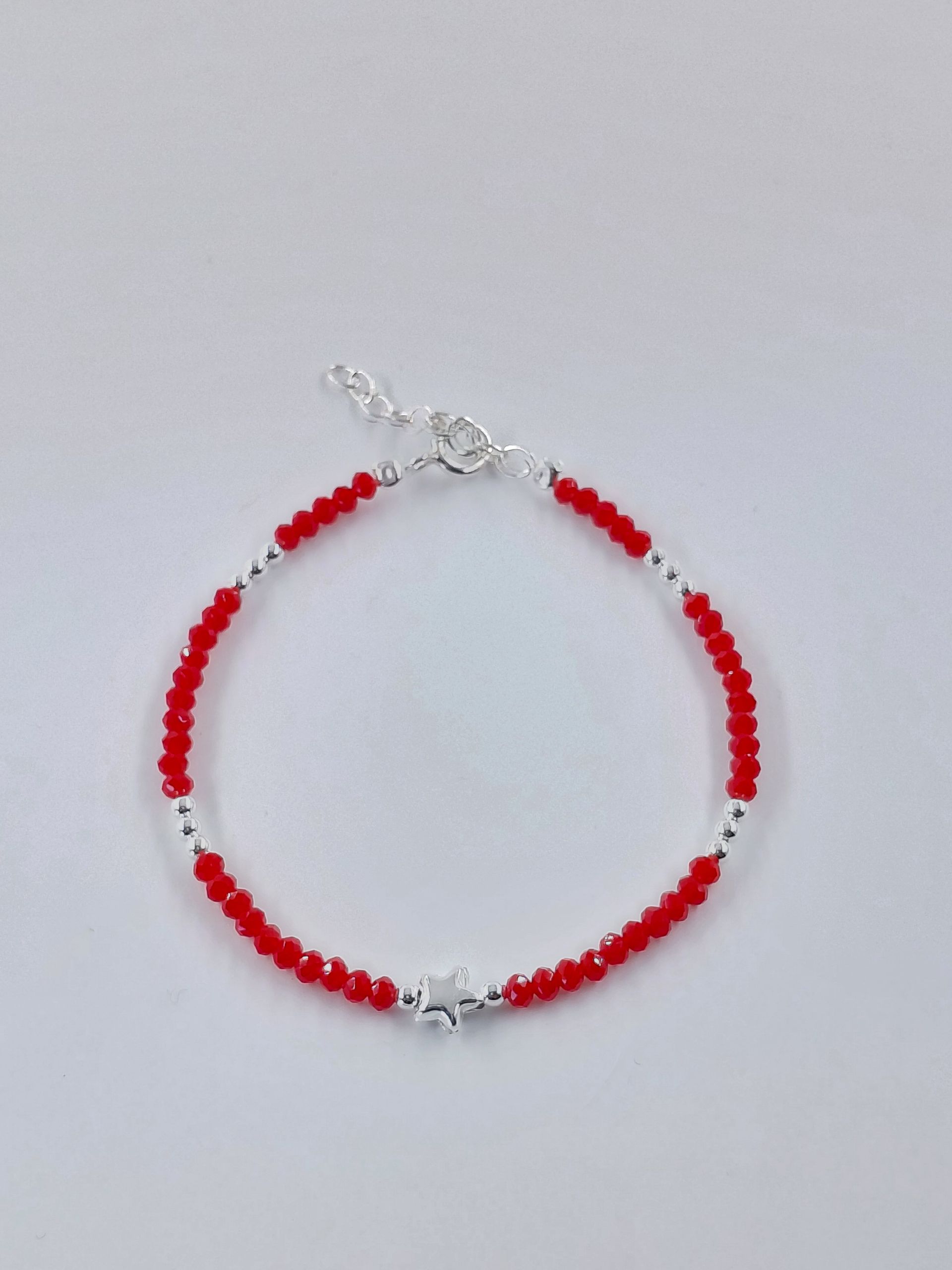 Pulsera de cuentas rojas y plateadas sobre un fondo gris claro