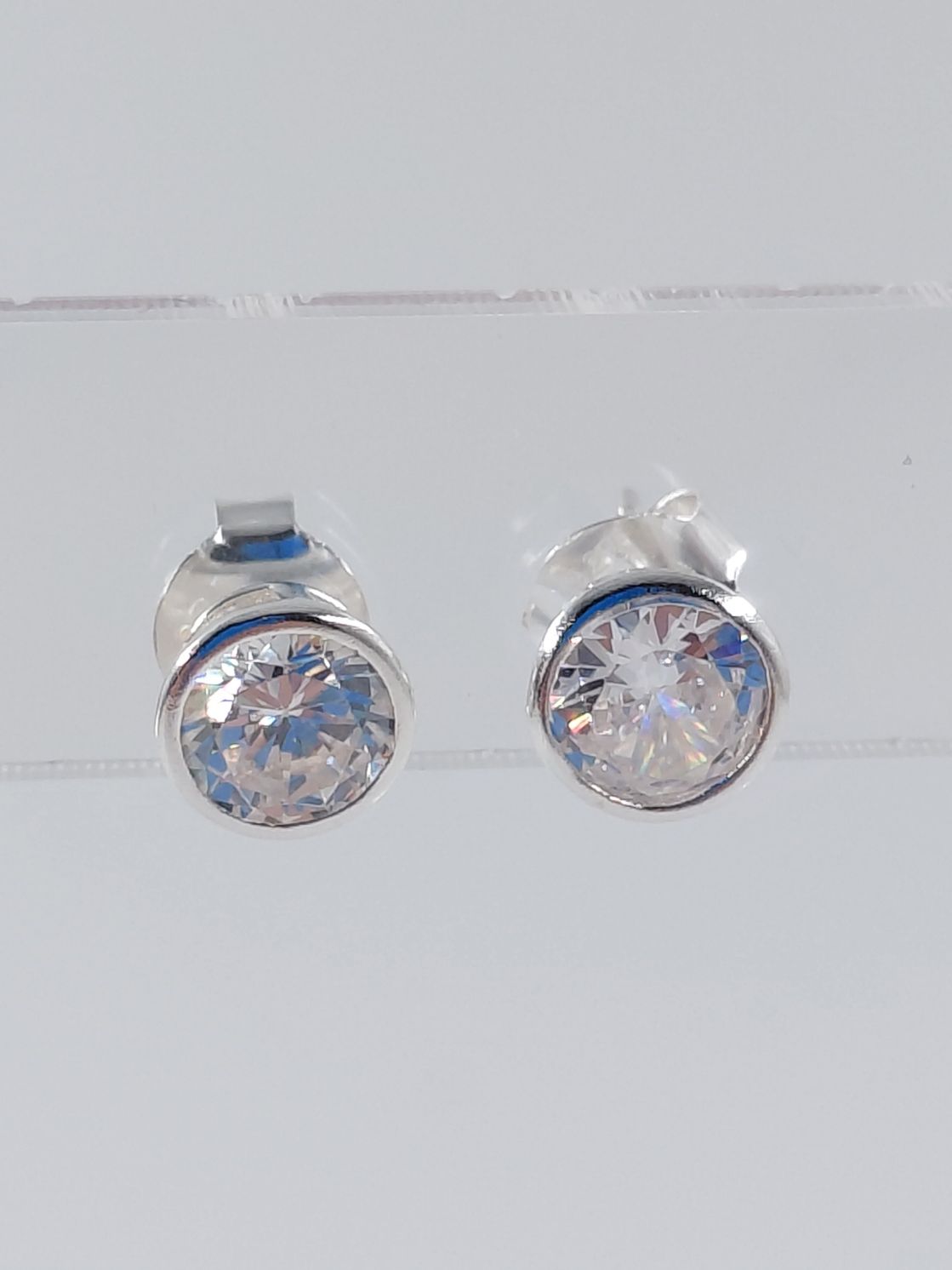 Par de pendientes de plata con piedras transparentes facetadas sobre fondo blanco.