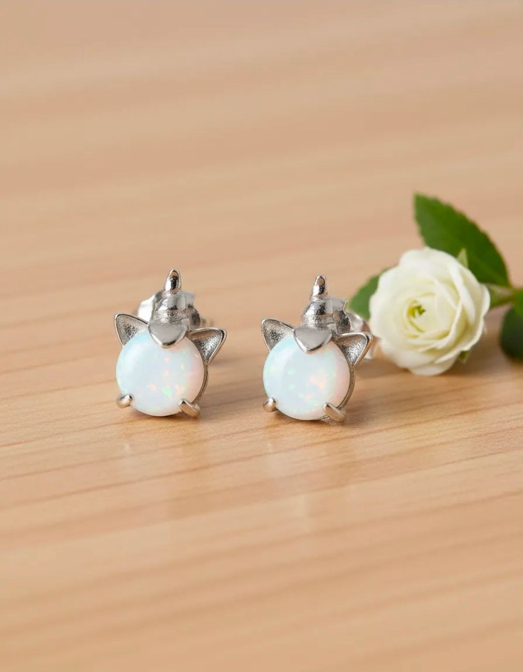 Pendientes de ópalo en forma de lágrima y conjunto de joyas a juego sobre una superficie de mármol blanco.