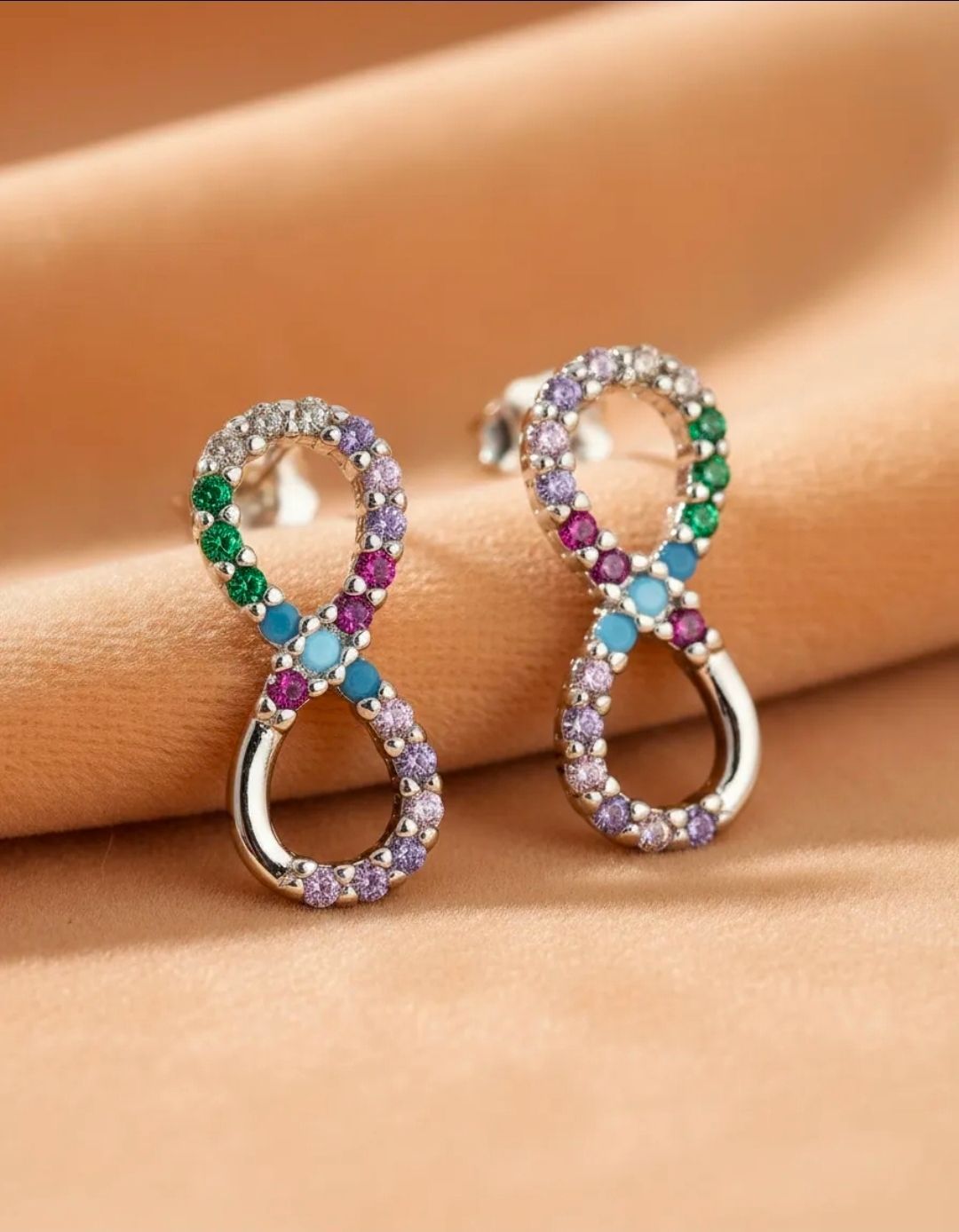 Dos pendientes de aro multicolores brillantes sobre una superficie gris claro.