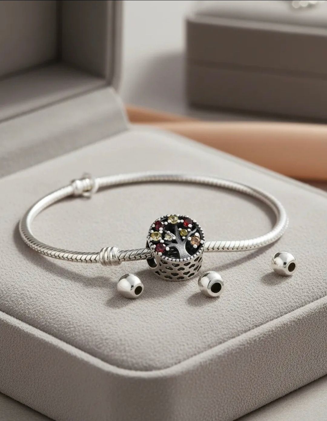Pulsera de plata con dije y pieza central de cristal redondo sobre un cojín de exhibición beige.