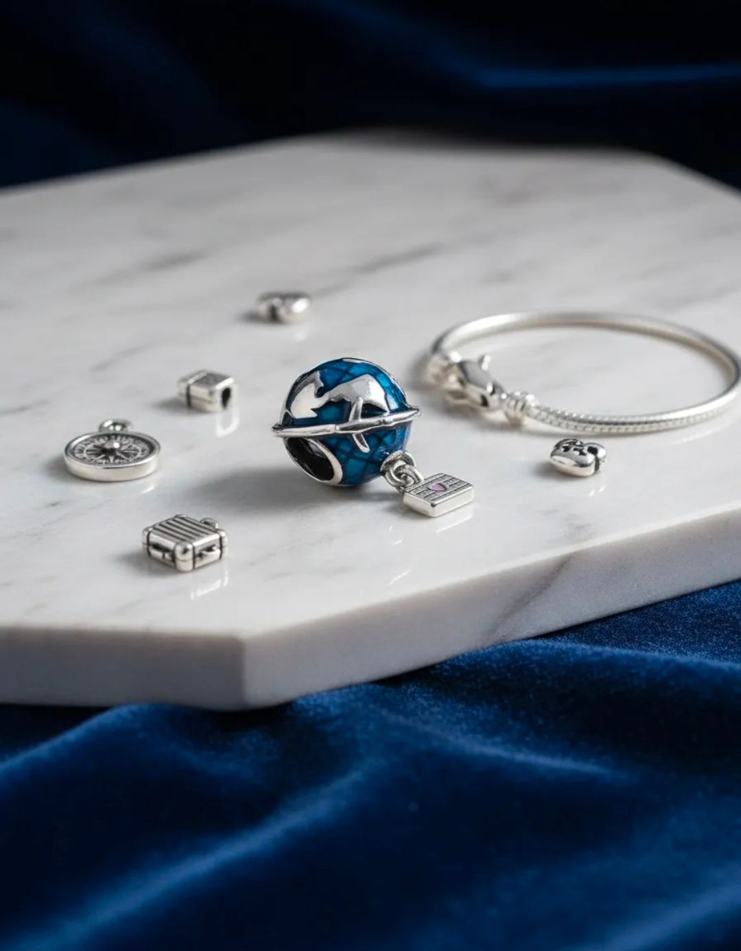 Conjunto de joyas azules y plateadas sobre una bandeja de mármol blanco sobre terciopelo azul oscuro.