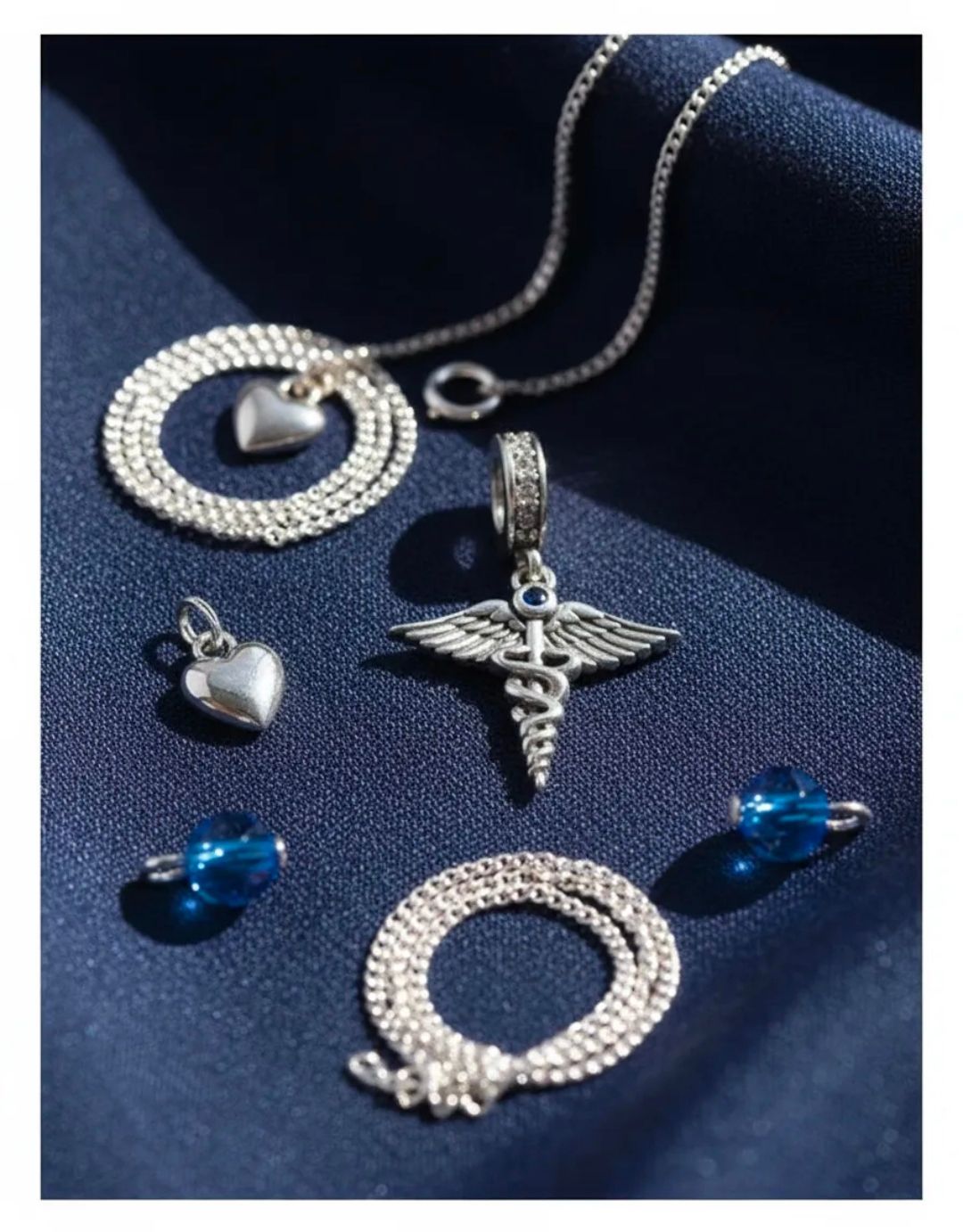 Colgante de caduceo de plata en una cadena sobre una chaqueta de traje oscura.