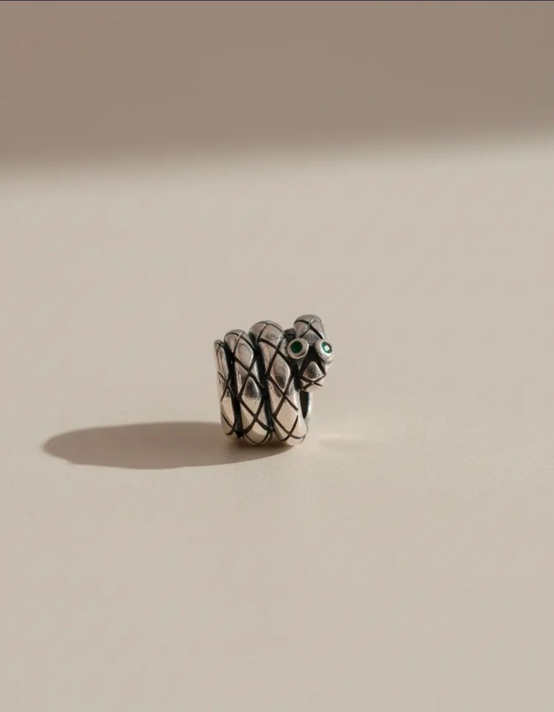 Pulsera de plata con dijes de cuentas negras y plateadas sobre una base de exhibición gris claro, con cuentas a juego cerca