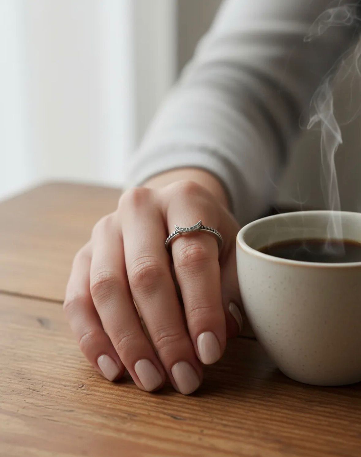 Anillo de plata con una banda curva engastada con piedras sobre una superficie de mármol blanco.