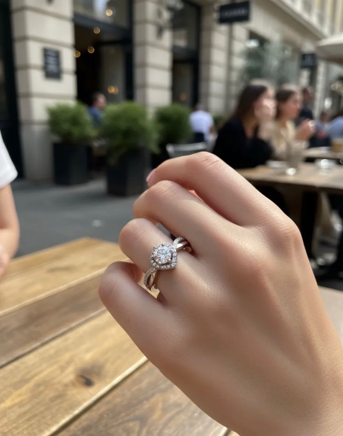 Anillo de compromiso de plata con diamante redondo sobre una superficie gris.