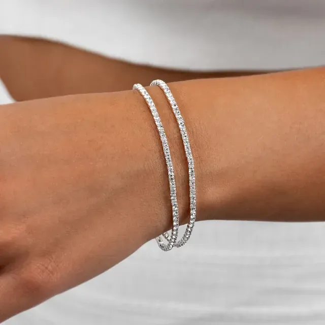 Primer plano de una muñeca con dos delicadas pulseras de cadena de plata.