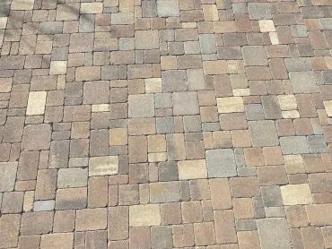 Close-up of a tan and gray brick paver surface with a random staggered pattern