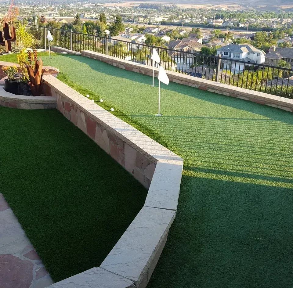 Rooftop terrace with green turf, low stone wall, and city view in the distance