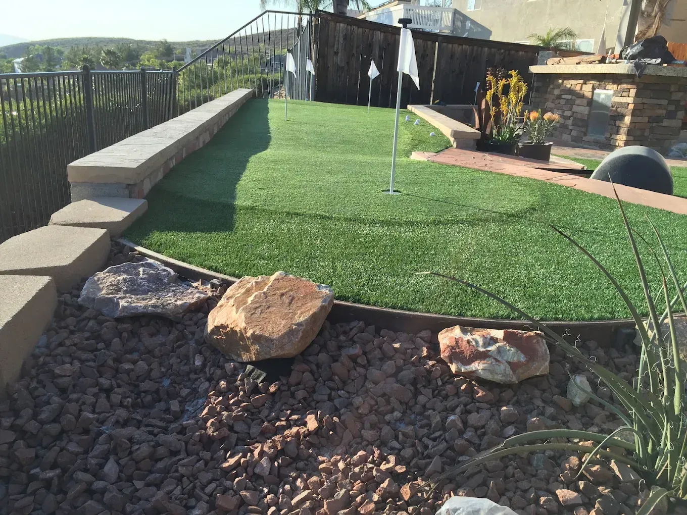 Landscaped backyard with artificial turf, rock garden, and a water fountain spray