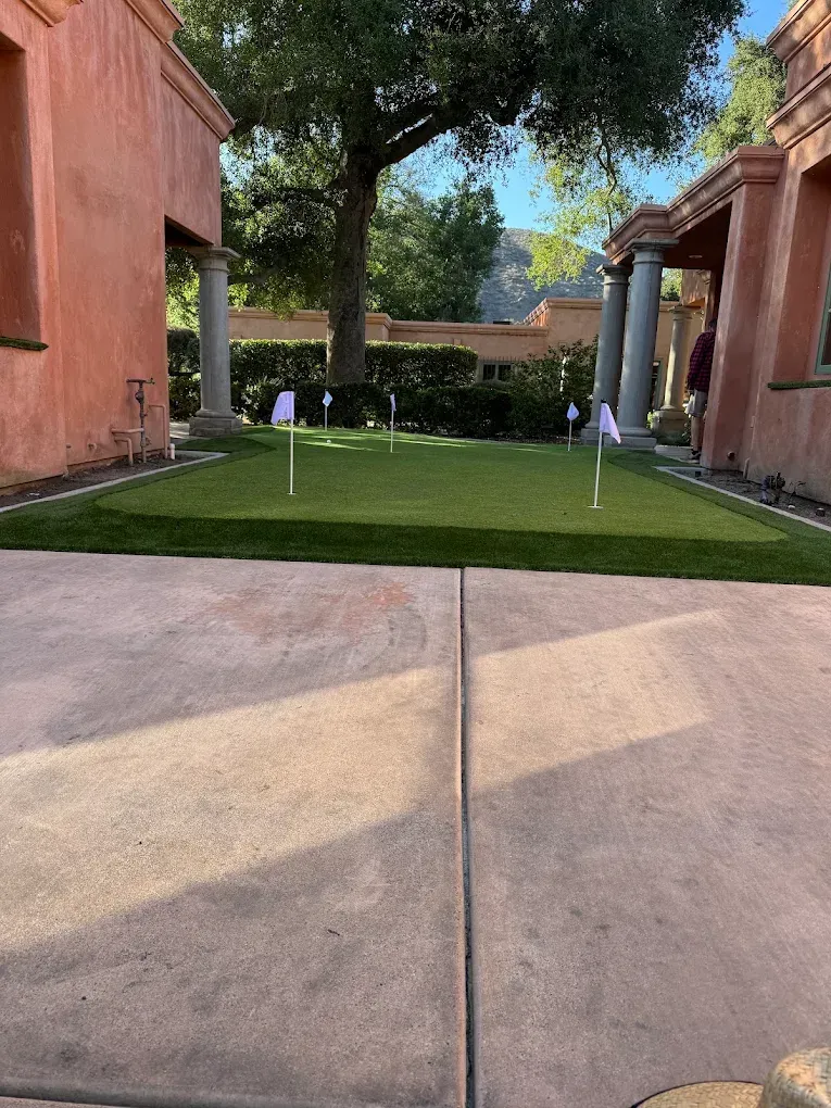 Courtyard with green lawn, small flag markers, and terracotta buildings framing a walkway