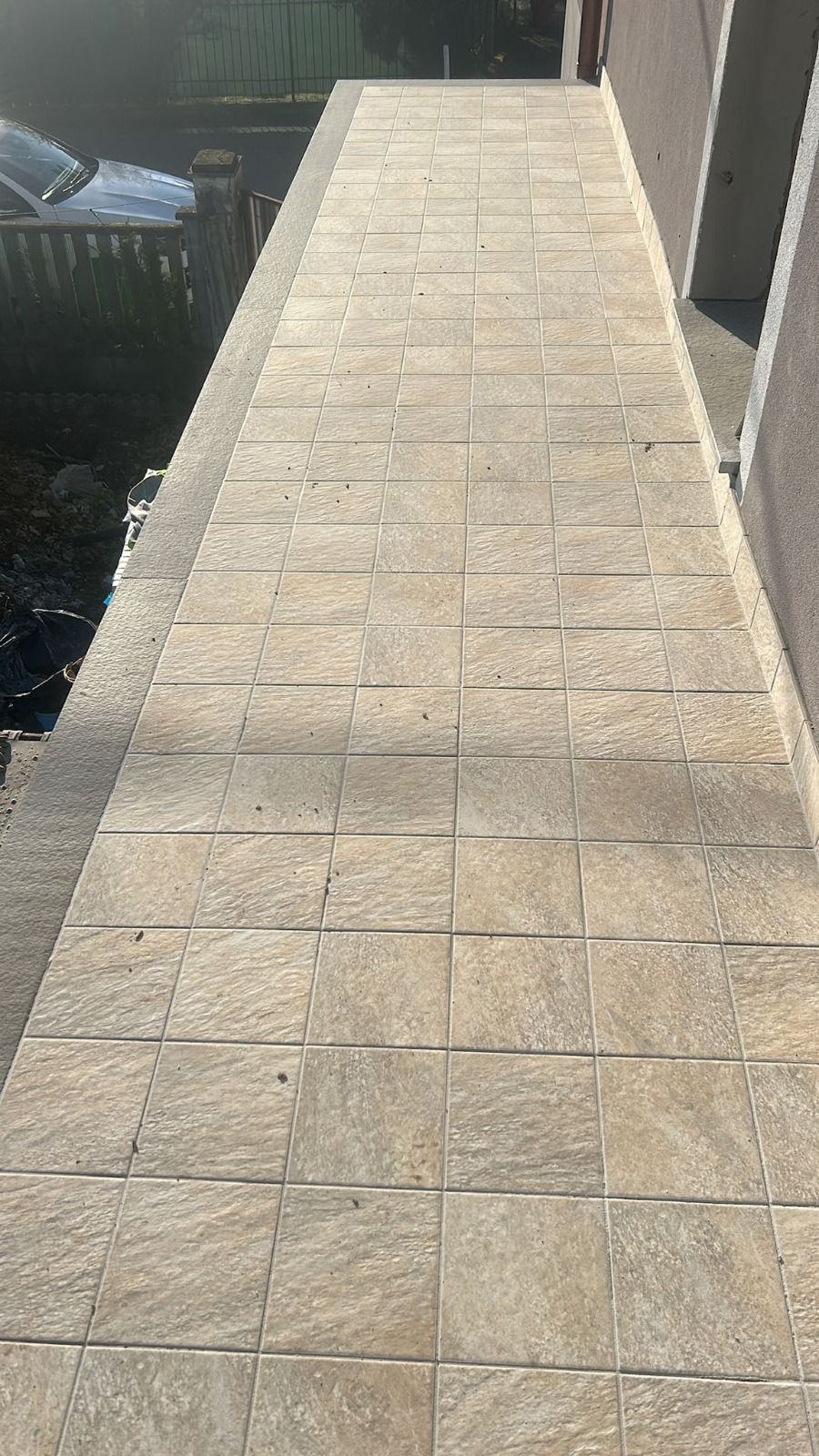 Passerella in pietra lungo il lato di un edificio, che conduce a un ingresso nascosto.