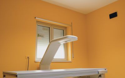 Sala visite mediche con lettino, lampada a soffitto e finestra su pareti arancioni