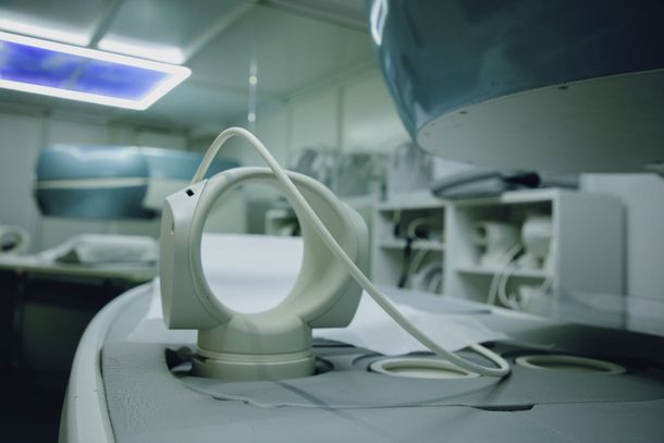 Scanner per immagini medicali in una stanza sterile, con lettino per il paziente e apparecchiature sopraelevate.