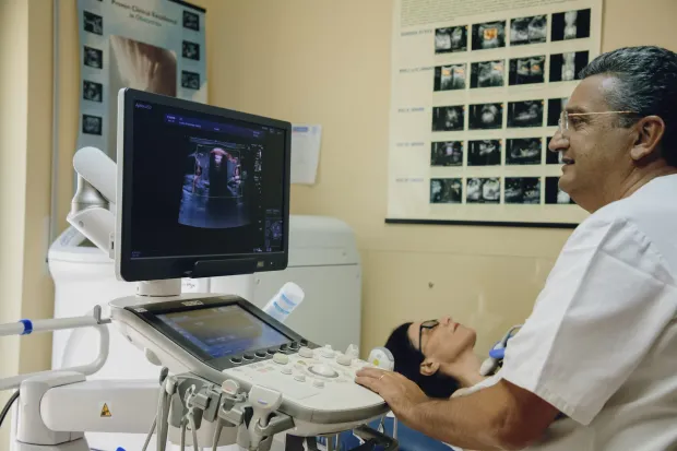 In una clinica, il medico esegue un'ecografia su un paziente, visualizzando l'immagine su un monitor.