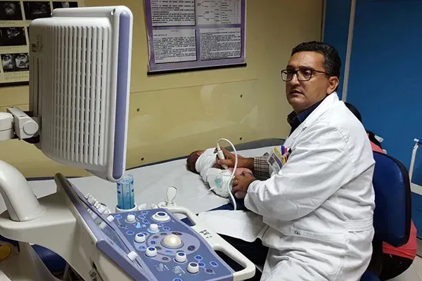 Un medico esegue un'ecografia in una clinica, seduto accanto al paziente.