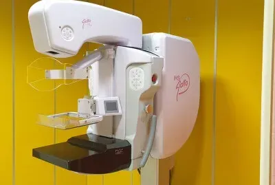 Apparecchio per mammografia con pannelli rosa e bianchi su una parete gialla