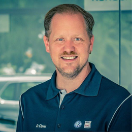 Ein Mann trägt ein blaues Poloshirt mit einem Volkswagen-Logo darauf