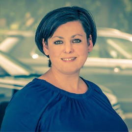 Eine Frau in einem blauen Hemd lächelt in die Kamera