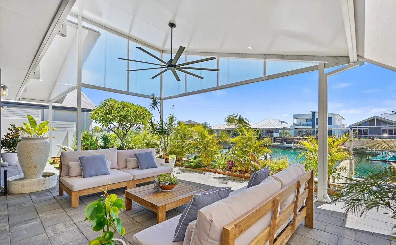 Covered outdoor living area with sofas, tropical planting and a waterfront outlook