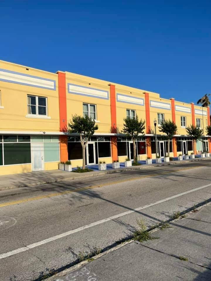 A row of yellow and orange buildings with trees in front of them