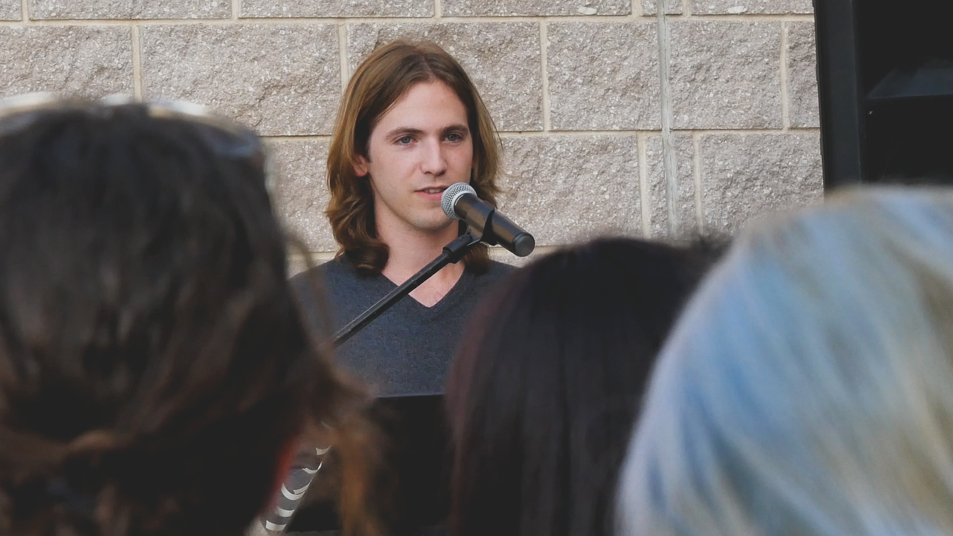 A man is singing into a microphone in front of a crowd of people.