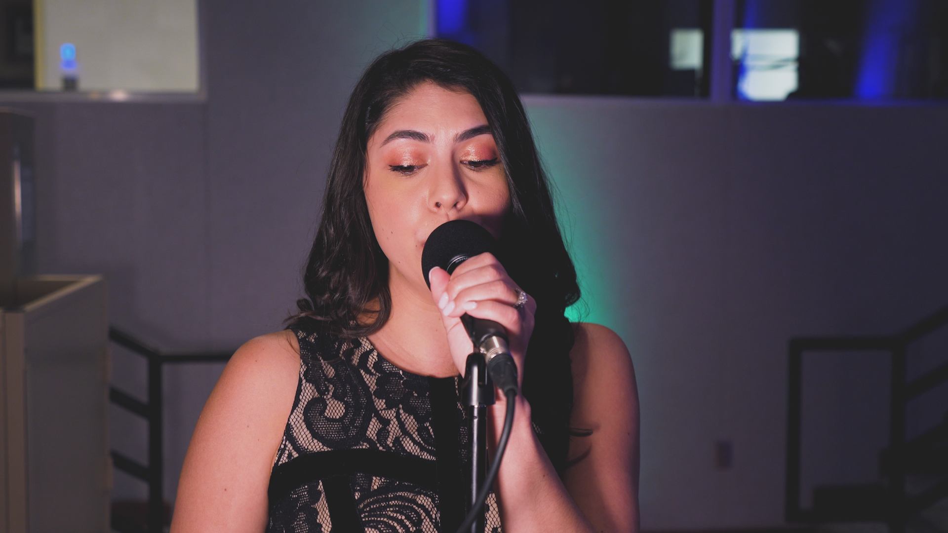 A woman is singing into a microphone in a dark room.