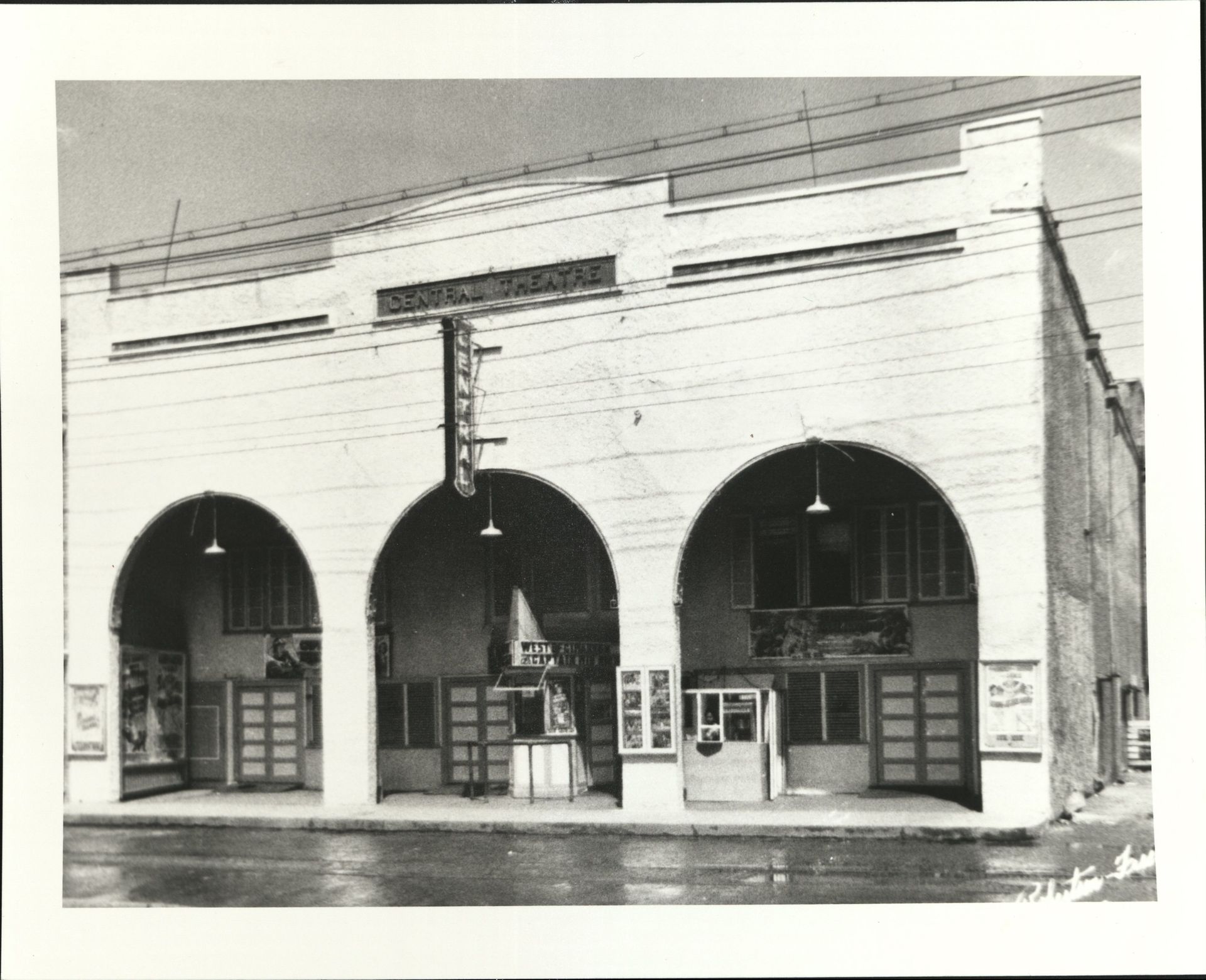 A black and white photo of a building with arches and a sign that says ' theatre ' on it