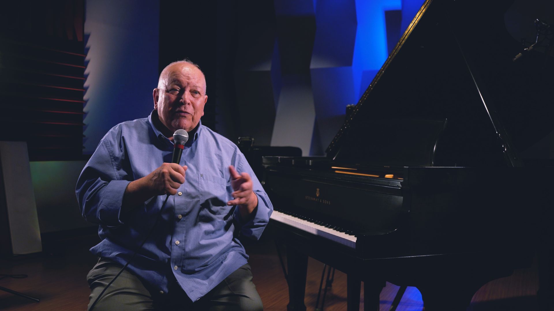 a man is sitting in front of a piano holding a microphone .