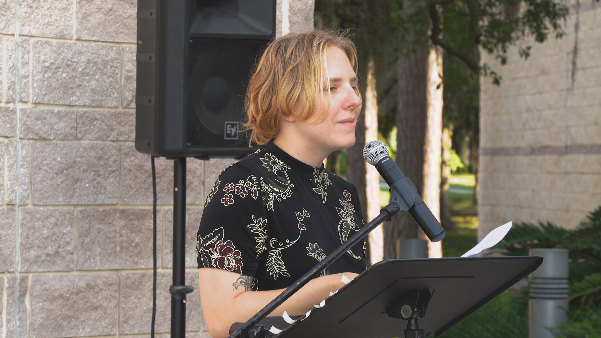 A person is standing at a podium speaking into a microphone