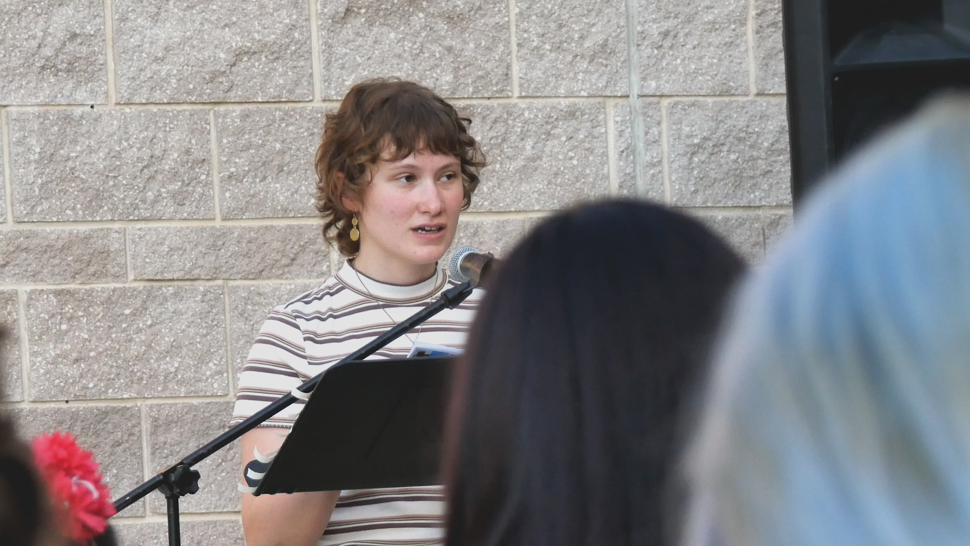 A woman is speaking into a microphone in front of a crowd.