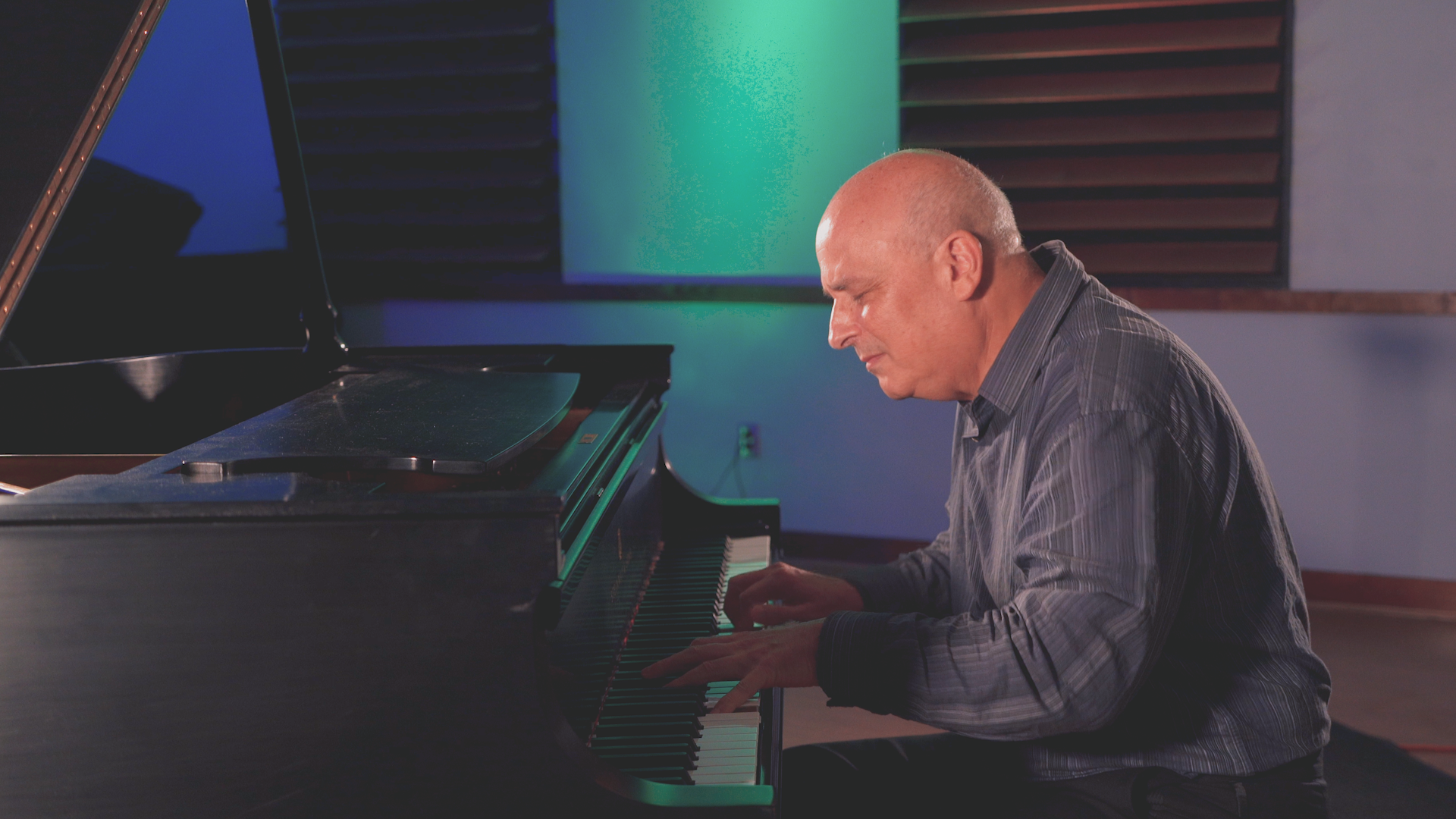 A man is playing a piano in a room.