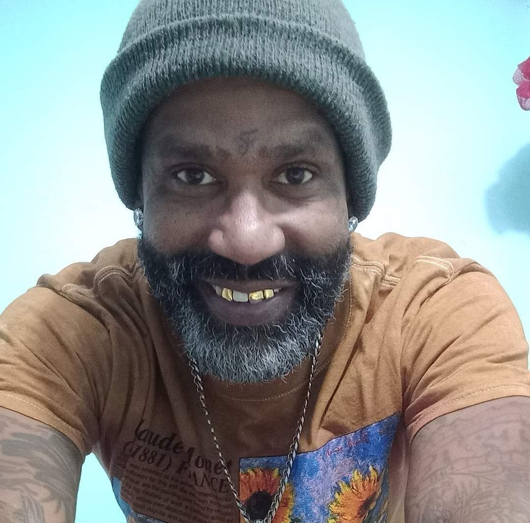 A man with a beard and a beanie is smiling for the camera.