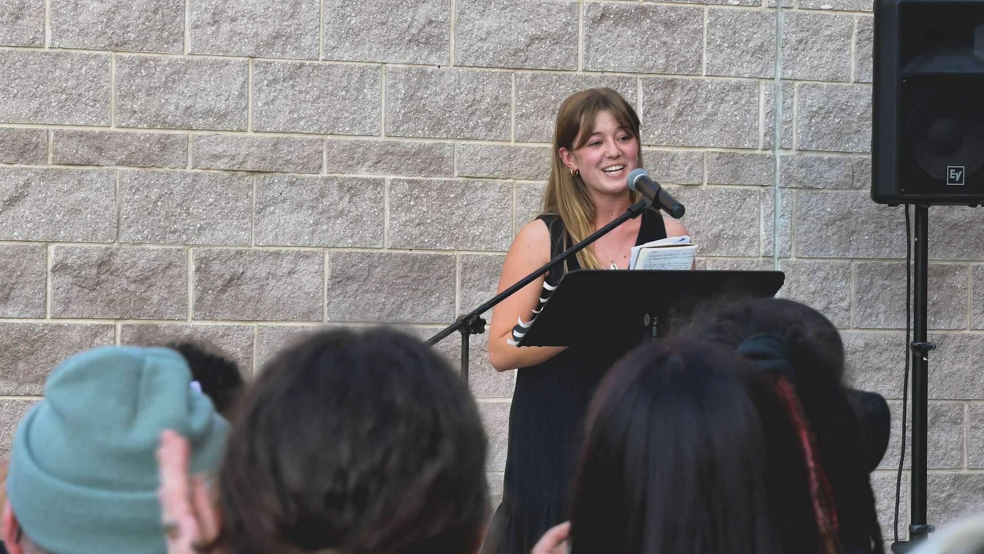 A woman is standing at a podium speaking into a microphone.