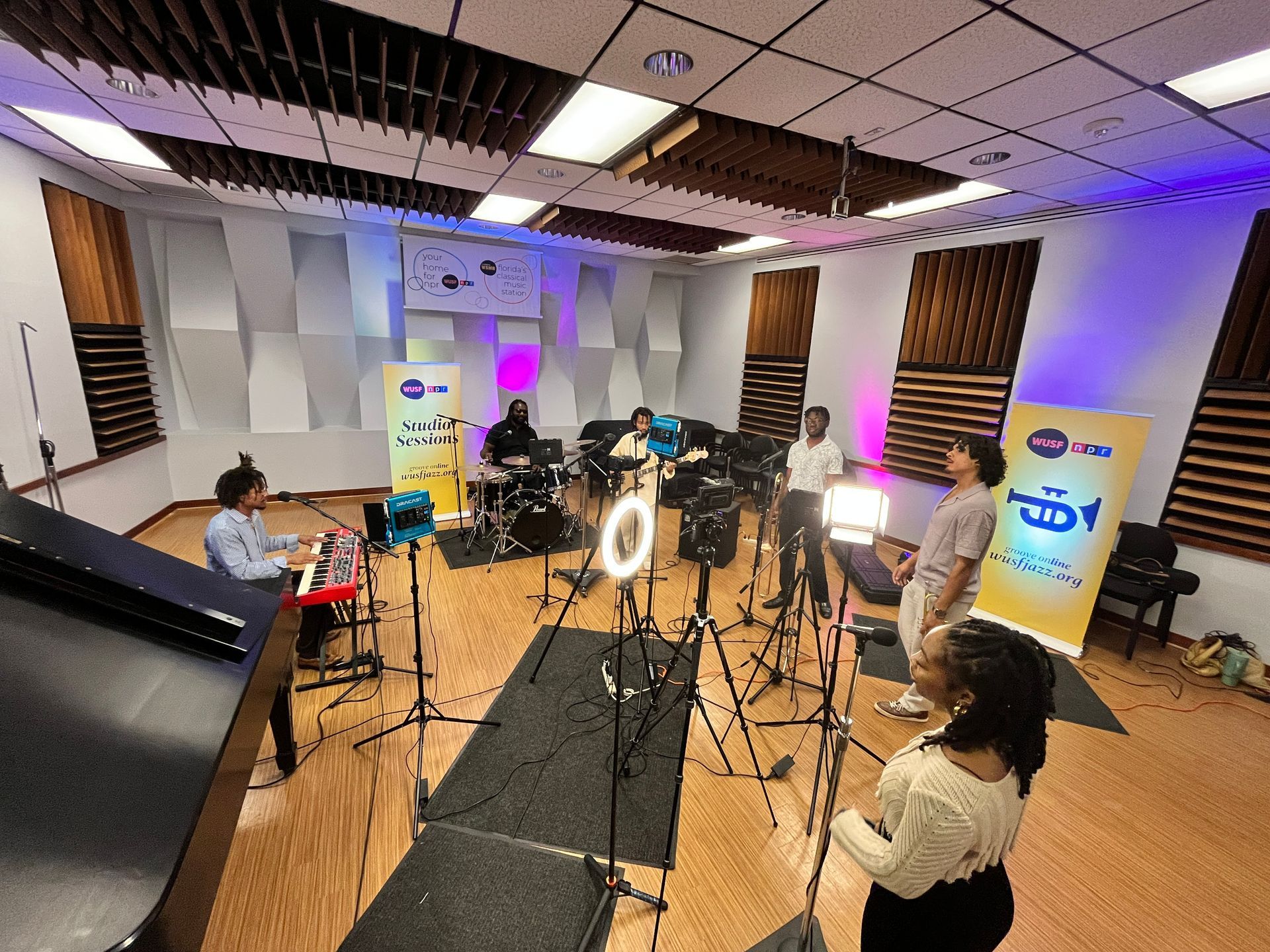 A group of people are standing in a recording studio.