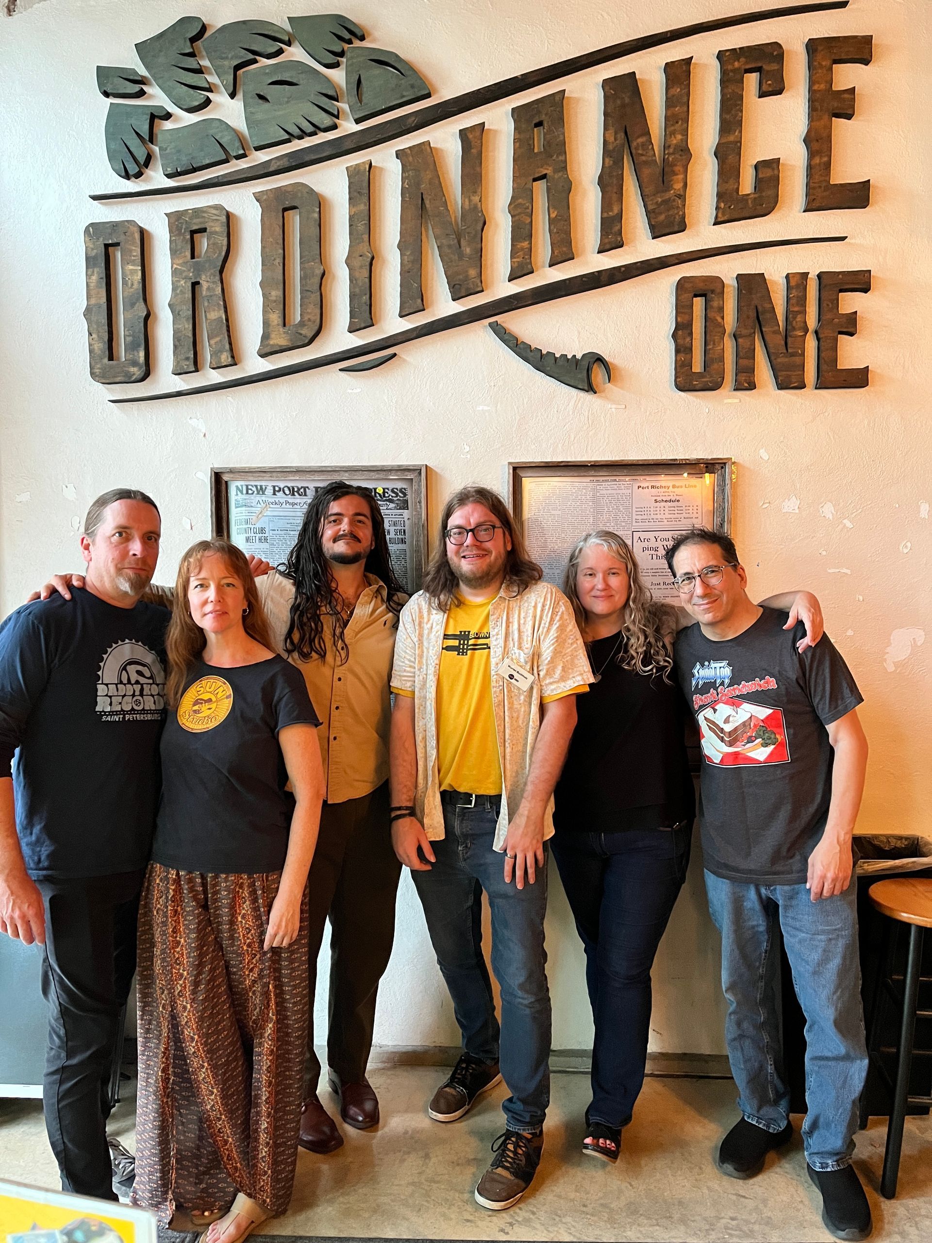 A group of people are posing for a picture in front of a sign that says ordinance one.
