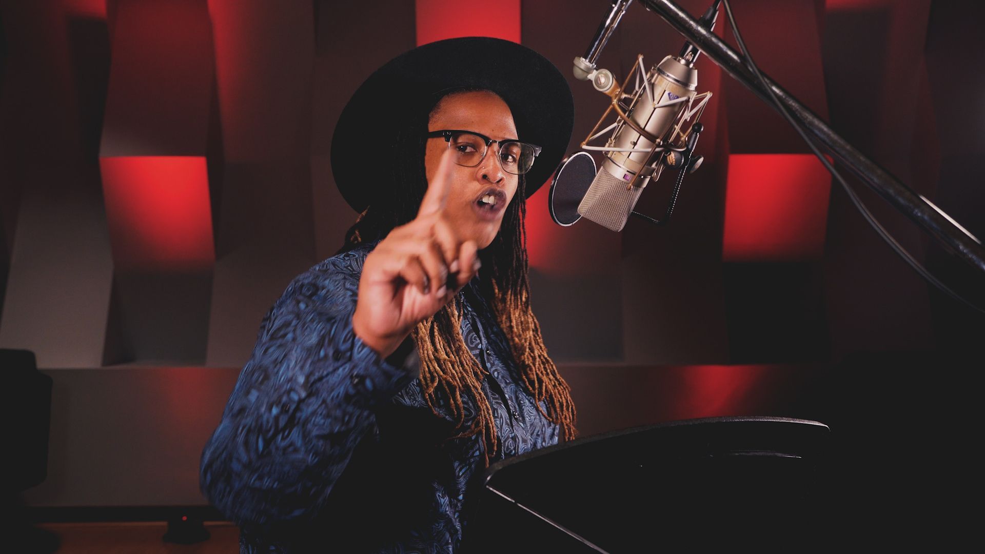 A woman is singing into a microphone in a recording studio.