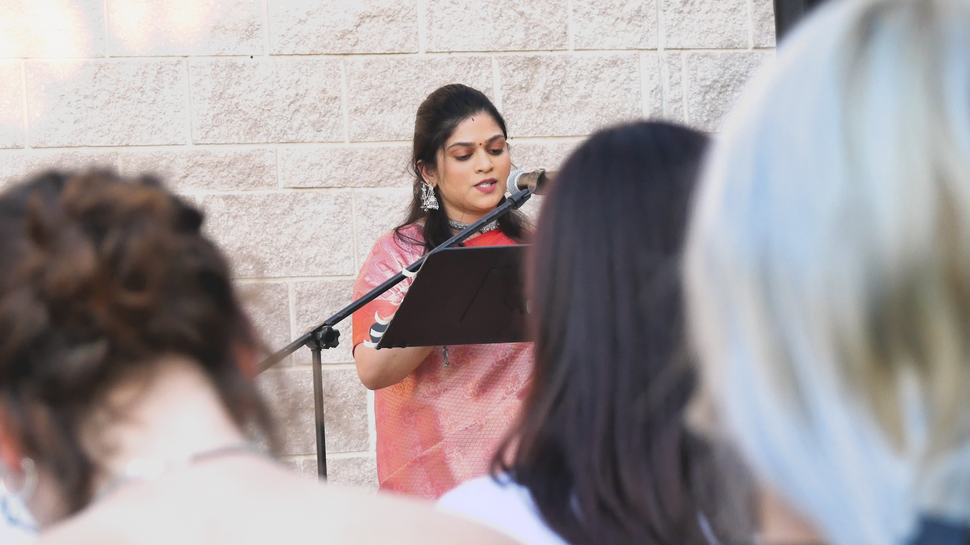 A woman is standing in front of a microphone giving a speech to a group of people.