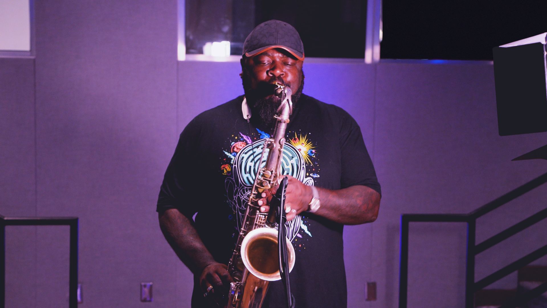A man is playing a saxophone in a dark room.