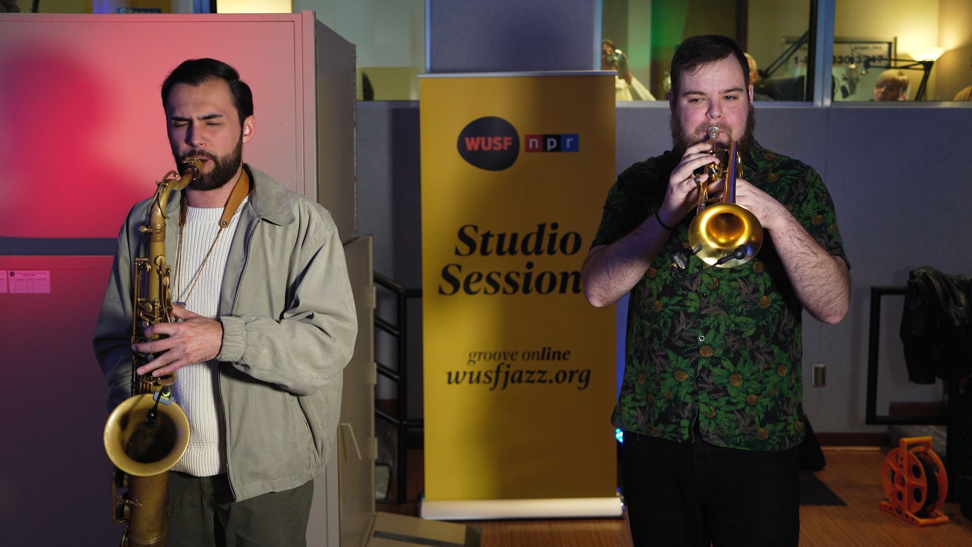 Two saxophonists performing onstage beside a Studio Session banner.